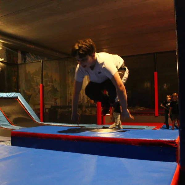 Adolescent réalisant une figure de trampoline acrobatique avec un coach chez SALTO