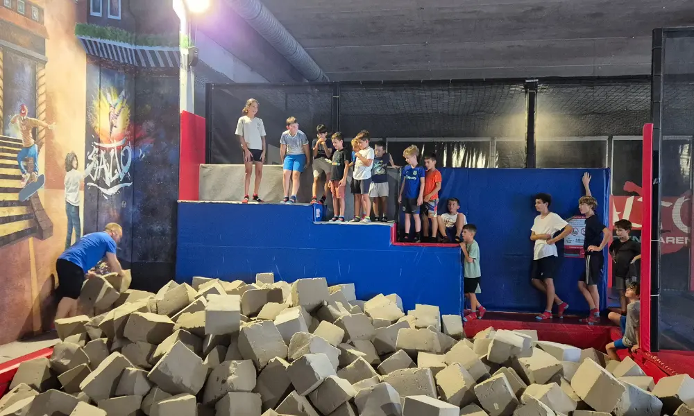 Enfants jouant dans la fosse à mousse climatisée du trampoline park SALTO pendant une journée de forte chaleur.